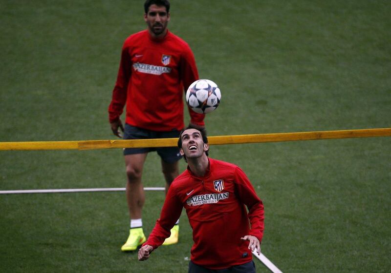 Atletico Madrid player Diego Godin, front, heads the ball next to teammate Raul Garcia as they attend Monday's club training session for the Champions League final. Sergio Perez / Reuters / May 19, 2014