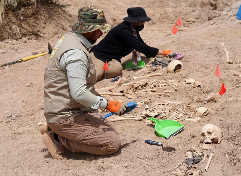 Forensics experts exhume human remains at the site.