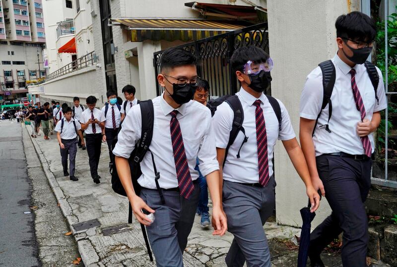 Students wearing masks, walk along with their formal uniforms near Diocesan Boys' School in Hong Kong. AP Photo