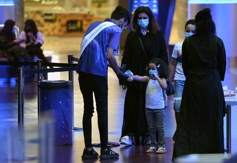 A man measures the temperature of a child as a family enter a movie theatre at a cinema in Riyadh. AFP
