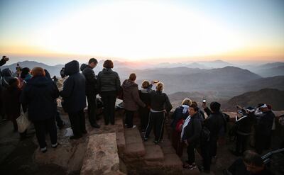 Tourists stand to watch the sunrise after scaling Mount Catherine, above the 6th-century Greek Orthodox Christian monastery of Saint Catherine, near the Egyptian town of the same name in the Sinai peninsula in 2021. AFP