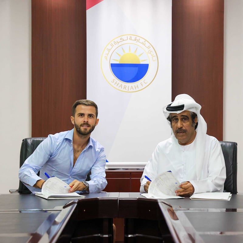 Miralem Pjanic puts pen to paper on his contract with Sharjah. Photo: Sharjah FC