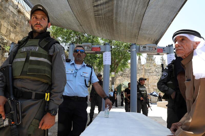 Israeli police officers stand guard next to newly installed metal detectors as a Palestinian man stands nearby at the entrance to the compound known to Muslims as Noble Sanctuary and to Jews as Temple Mount, in Jerusalem's Old City. Ammar Awad / Reuters