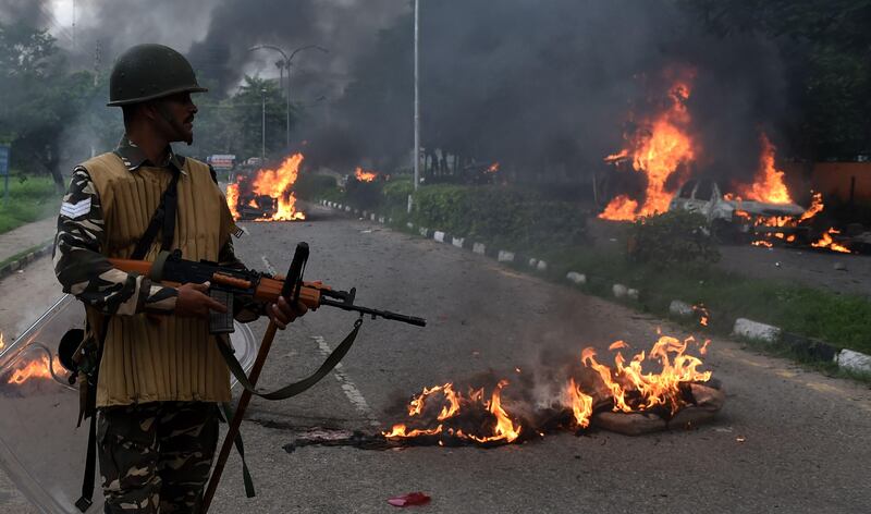 Indian security personnel look at burning vehicles set alight by rioters. Money Sharma / AFP Photo