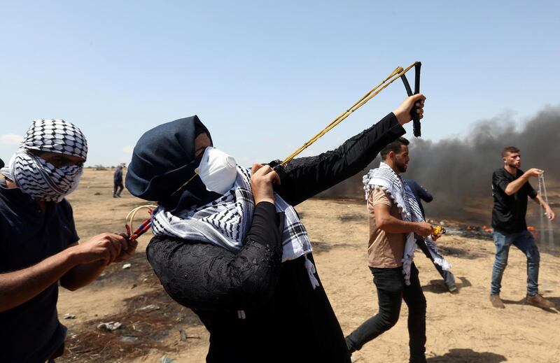 A female demonstrator uses a slingshot to hurl stones at Israeli forces during the final week of border protests in the southern Gaza strip. Ibraheem Abu Mustafa / Reuters