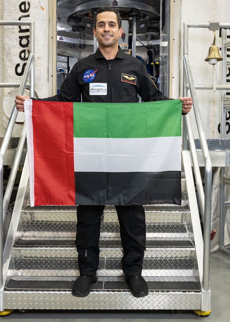 Mr Al Romaithi holds up a UAE flag outside the Hera habitat. MBRSC