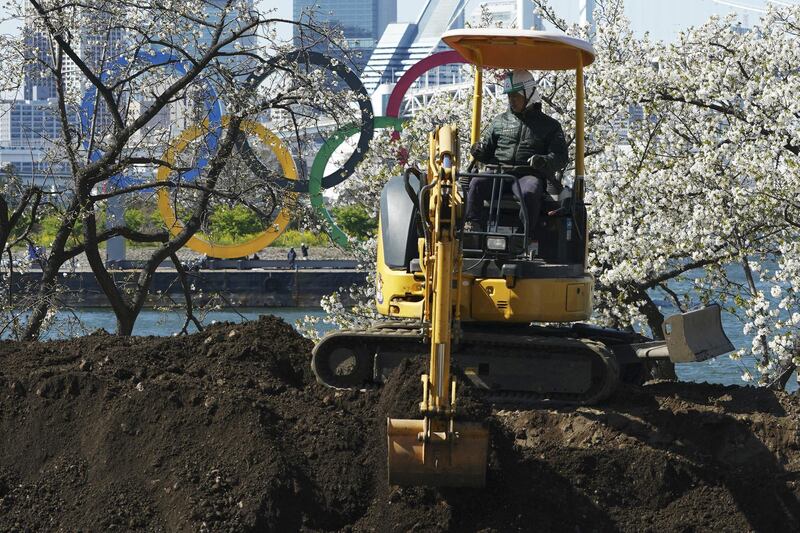 A worker operates an excavator near the Olympic rings at Tokyo's Odaiba district. AP