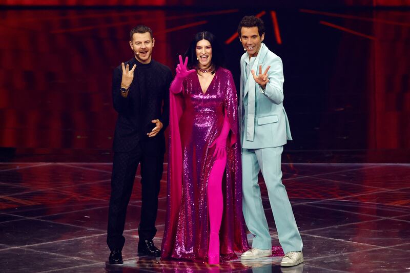 Hosts Alessandro Cattelan, Laura Pausini and Mika gesture on stage. Reuters