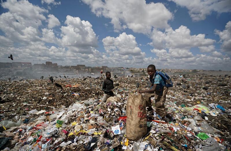 Peter, 12, right, scavenges pieces of paper and card from garbage for a living from among the garbage at the dump in the Dandora slum of Nairobi, Kenya. AP Photo