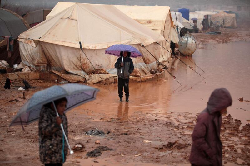 Syrian children who fled battles in the southern countryside of the Idlib province walk through mud after heavy rainfall in a camp for displaced people in Kafr Dariyan situated at a short distance from Syria's border with Turkey.   AFP