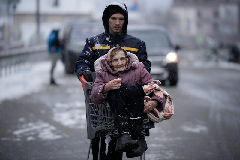 An elderly woman is carried in a shopping cart after being rescued from Irpin, on the outskirts of Kyiv, Ukraine. AP