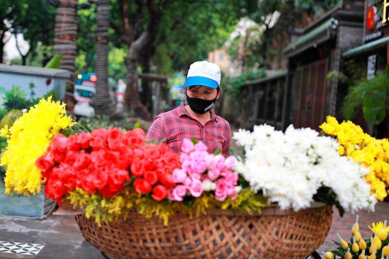 A flower vendor wearing a face mask to protect against the coronavirus waits for customers in Hanoi, Vietnam. AP Photo