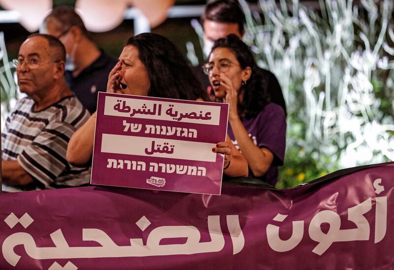 A woman chants slogans as she holds a sign reading in Arabic and Hebrew "police racism kills" while standing behind a banner reading in Arabic "I don't want to be the victim", during a protest against the government's insufficient action towards rising violence levels within the Arab community, outside the home of Public Security Minister Omer Bar-Lev in the northern Israeli town of Kokhav Yair.  AFP