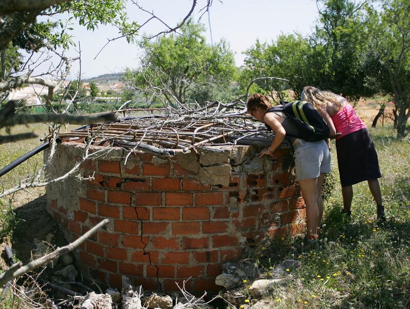 British tourists look down a well while searching for Madeleine McCann in wasteland in May 2007.