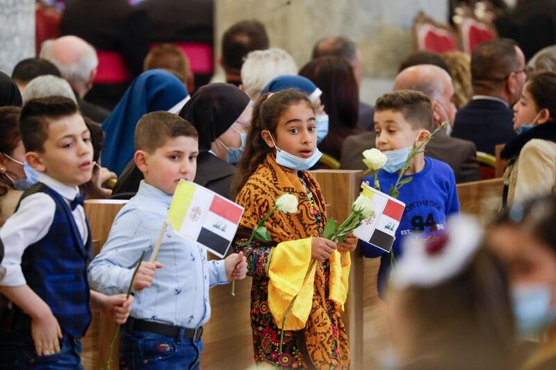 Children with flags wait for Pope Francis to arrive at a meeting with the Qaraqosh community at the Church of the Immaculate Conception. AP Photo