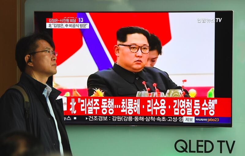 A man walks past a television news screen reporting about a visit to China by North Korean leader Kim Jong Un, at a railway station in Seoul on March 28, 2018. Jung Yeon-je / AFP