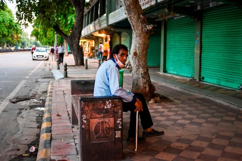 A security guard rests sitting on a bench in front of a row of closed shops in New Delhi on August 31, 2020. / AFP / Jewel SAMAD
