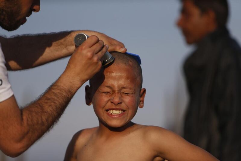 A migrant boy has a haircut in a makeshift camp at the border crossing at the northern Greek border point of Idomeni, Greece. Stranded migrants are spending their days in a makeshift camp near the railway station and waiting for borders to be opened. Amel Emric / AP