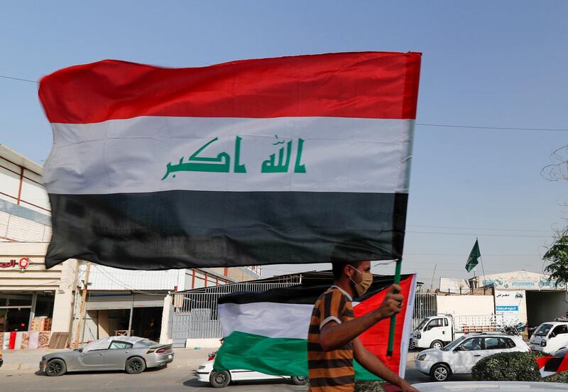 A member of Kataib Hezbollah paramilitary group holds an Iraqi flag and travels in a vehicle as he takes part in a parade ahead of the annual Quds Day, or Jerusalem Day, during the Muslim holy month of Ramadan, in Baghdad, Iraq May 6, 2021. REUTERS/Thaier Al-Sudani