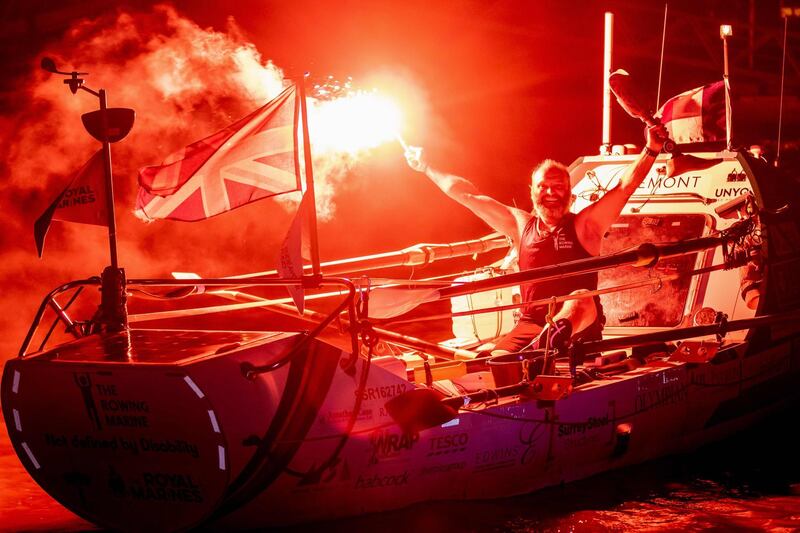 Lee Spencer holds a red flare and his prosthesis as he arrives in Cayenne, French Guiana, after smashing solo Atlantic rowing record from mainland Europe to South America. AFP