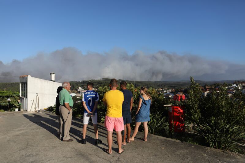 People keep their distance from a nearby forest fire in the Landal district of Caldas da Rainha in Portugal. AP