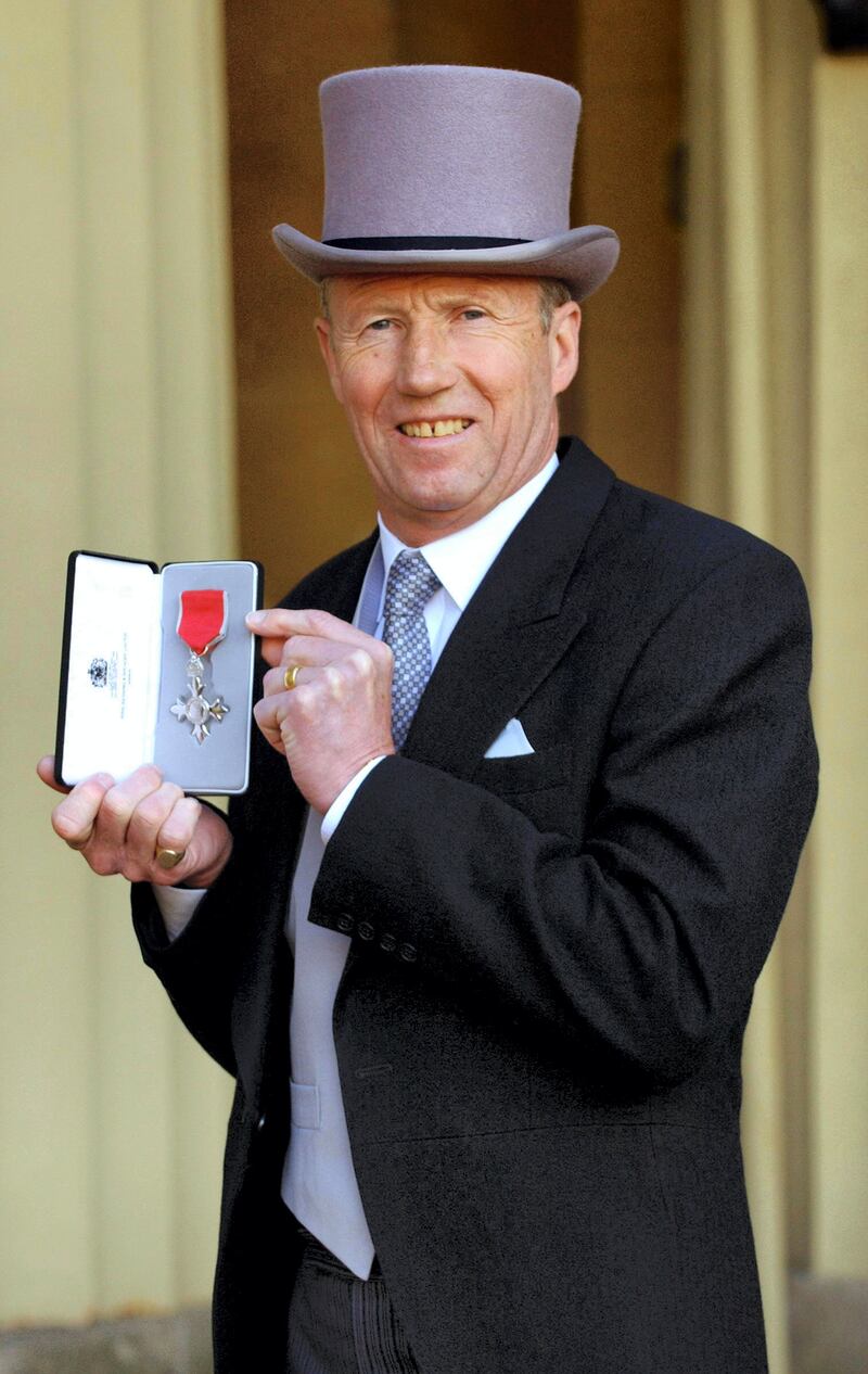 Former Manchester City footballer Colin Bell stands with his MBE after his investiture by Britain's Queen Elizabeth II at Buckingham Palace, London, 27 April, 2005.                  AFP PHOTO/FIONA HANSON/WPA POOL/PA (Photo by FIONA HANSON / POOL / AFP)