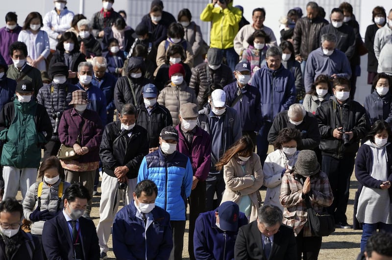 Visitors pray for a minute of silence for the victims of 2011 Tsunami and earthquake during the Olympic "Flame of Recovery" display ceremony. AP