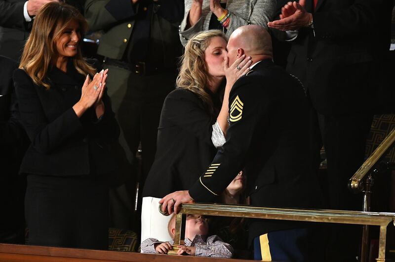 Sgt Townsend Williams (R) kisses his wife Amy (C) after returning from deployment in Afghanistan as First Lady Melania Trump applauds during the State of the Union address at the US Capitol in Washington, DC.  AFP