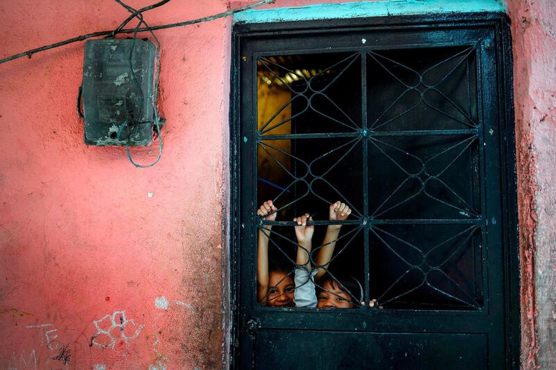 Children play behind the door in Petare slum in Caracas, Venezuela. AFP