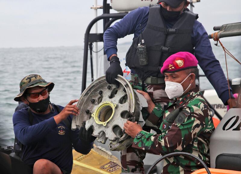 Indonesian Navy divers show parts of an aircraft recovered from the water. AP Photo