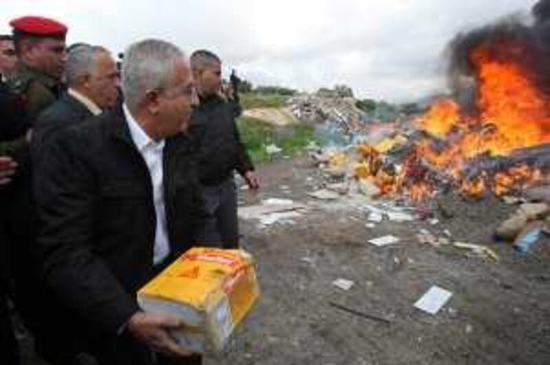 Palestinian Prime Minister Salam Fayyad, throws a package into a fire set to burn products from Jewish settlements,  in the west Bank of Salfit Tuesday, Jan 5, 2010.  The Palestinians have launched a boycott of Israeli products made in Jewish settlements in the West Bank.(AP Photo/Nasser Ishtayeh) *** Local Caption ***  JRL111_APTOPIX_MIDEAST_ISRAEL_PALESTINIANS_.jpg