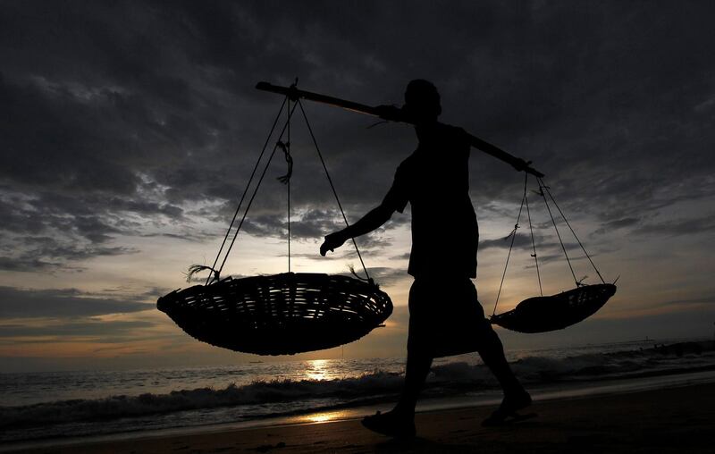 A fisherman carries empty baskets on a pole as he walks on the beach at sunset, in Colombo March 26, 2013.  REUTERS/Dinuka Liyanawatte (SRI LANKA - Tags: SOCIETY) *** Local Caption ***  COL01_SRILANKA-_0326_11.JPG