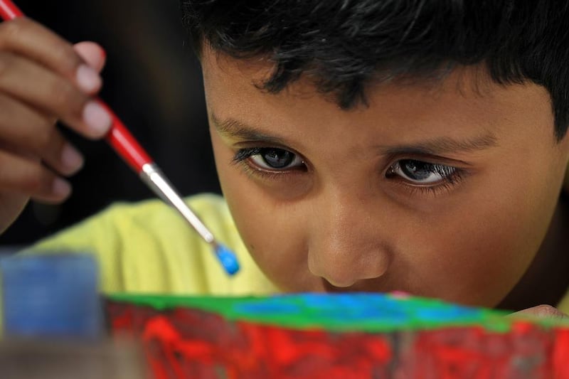 Elvin Mathew, 6, focuses on his painting on Saturday at the Picture This art workshop for children with autism at Umm Al Emarat Park in Abu Dhabi. They and other children created their masterpieces, which will be on show at the park. Delores Johnson / The National