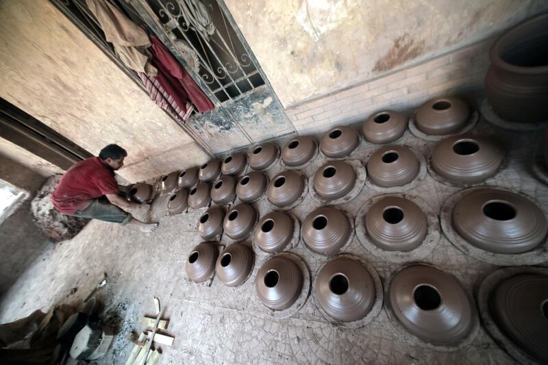 An Egyptian worker sorts clay pots to dry before displaying them for sale at one of the traditional pottery workshops, in Old Cairo, Egypt.