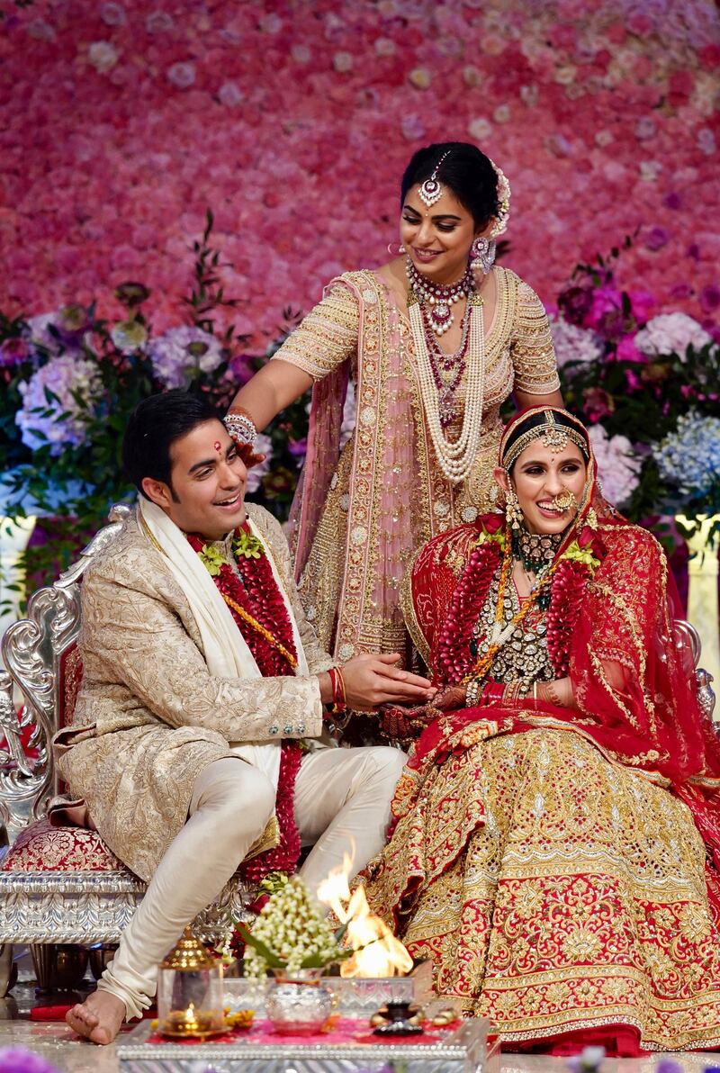 Isha, centre, daughter of Reliance Industries Chairman Mukesh Ambani, gestures as her brother Akash Ambani, left, and sister-in-law Shloka Mehta perform a ritual at their wedding ceremony in Mumbai, India on Saturday. Photo: Reliance Industries Limited Photo via AP
