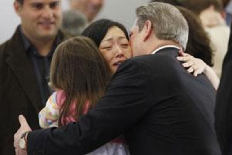 Euna Lee hugs the former US vice-president Al Gore while holding her daughter Hana after arriving back in the US.