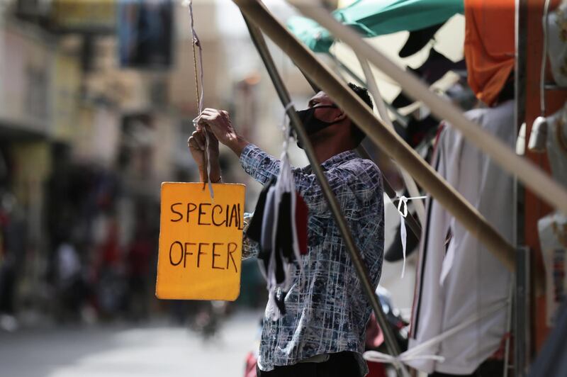 A man wearing a protective face mask puts up a sign in front of his store in a street of Manama, Bahrain. EPA