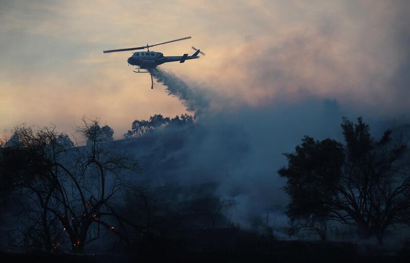 A firefighting helicopter makes a water drop on the Lilac Fire in Bonsall, California. Mike Blake / Reuters
