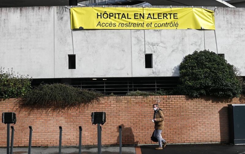 A man walks under a sign hanging outside the Dunkirk hospital center that reads 'Hospital on alert, access is controlled '. AFP