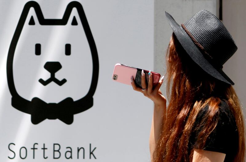 FILE PHOTO: A woman using her smart phone walks outside a branch of SoftBank Corp in Tokyo, Japan, August 6, 2015. REUTERS/Yuya Shino/File Photo