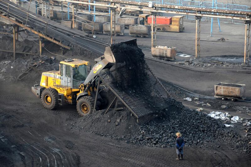 In this Feb. 20, 2017, photo, a worker watches as a digger dumps out a load of coal at a coal mine in Huaibei in central China's Anhui Province. The deputy head of the Chinese Cabinet agency in charge of energy policy for the world's second-largest economy, a former longtime executive in the state-owned coal industry, has been dismissed on graft charges, the country's anti-corruption agency said Tuesday, Jan. 23, 2018. (Chinatopix via AP)