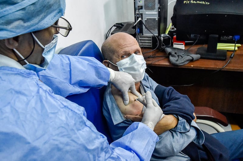 A medical worker administers a dose of Russia's Sputnik V vaccine on a man at a clinic in the city of Blida. AFP