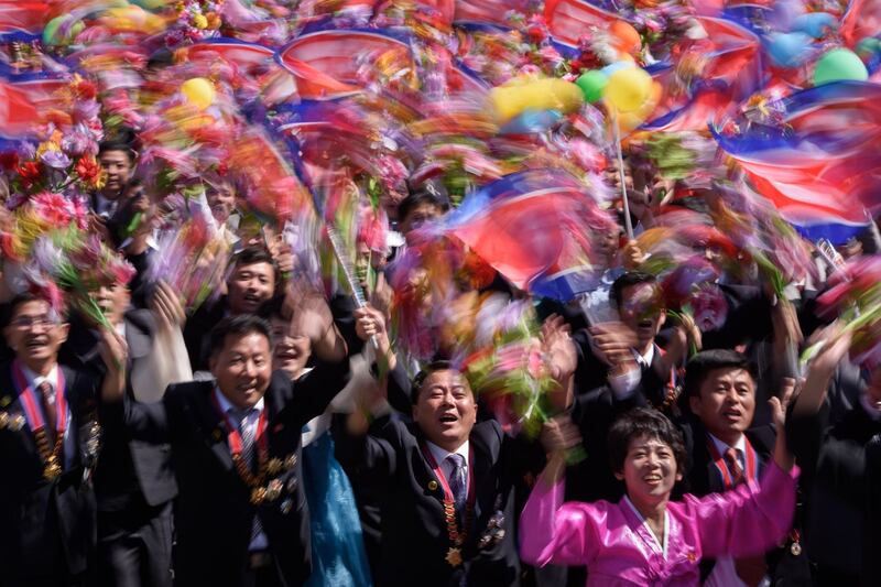 Participants wave flowers as they march past a balcony from where North Korea's leader Kim Jong Un was watching, during a mass rally on Kim Il Sung square in Pyongyang. AFP