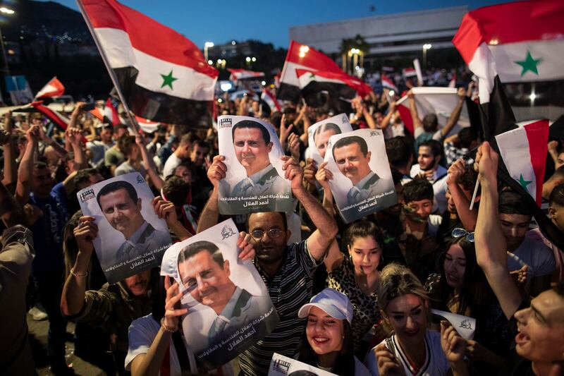 Supporters of Syrian President Bashar Al Assad attend a rally in Damascus in May 2021. Kenan Wakkaf, a critic of the Assad regime from Tartous, a stronghold of the president, says he has gone into hiding after soldiers came looking for him.  AP Photo