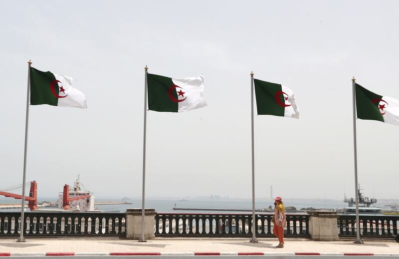 A woman walks next to Algerian flags in the capital, Algiers, on the eve of the country's 60th independence anniversary. EPA