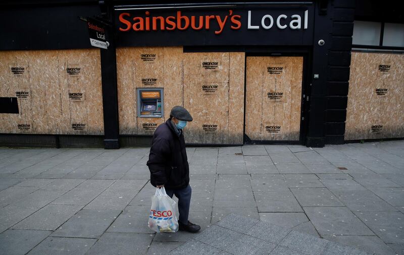 A man walks past a boarded up Sainsbury's local store in Liverpool. Reuters