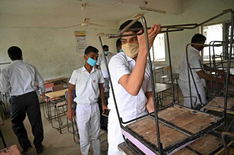 Pupils wearing face masks arrange desks in a classroom after their school was reopened in Colombo.  AFP