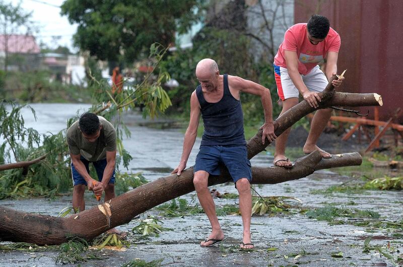 Men cut down a tree that fell due to strong winds as Typhoon Kammuri slammed Legazpi city, Albay province, southeast of Manila, Philippines. AP Photo