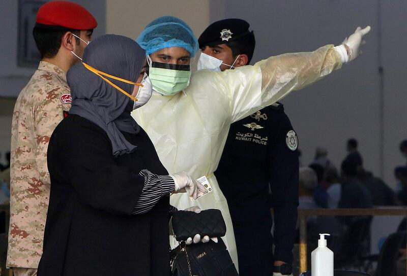 Kuwaiti healthy ministry workers prepare to scan expatriates living in Kuwait who returned from Egypt, Syria and Lebanon, as they arrive to a specified place to be tested for coronavirus in Kuwait City on March 12, 2020. / AFP / YASSER AL-ZAYYAT
