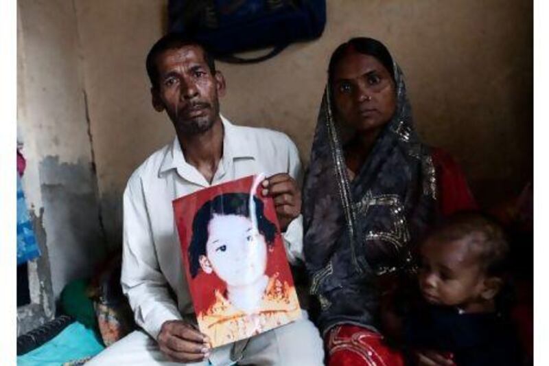 Raj Kumar Yadav and his wife, Hema Devi, with a photo of her missing daughter Kajal, one of thousands of children missing in Delhi.
